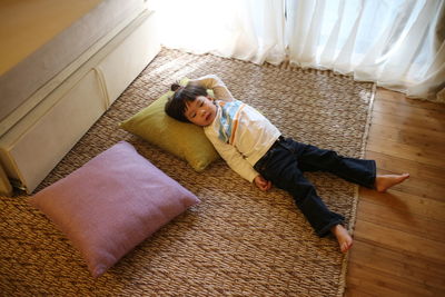 High angle view of boy relaxing on carpet at home