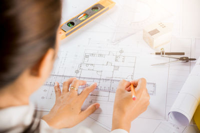 Midsection of architect working on blueprint in office