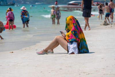 Woman wearing scarf while sitting at beach