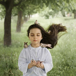 A girl with her hair down with birds sitting on her and in her hair