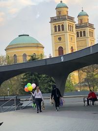 Rear view of people walking on building in city against sky