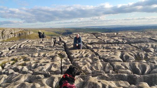 People enjoying vacation at malham cove against cloudy sky