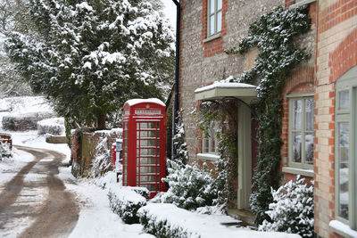 Snow covered street by buildings in city