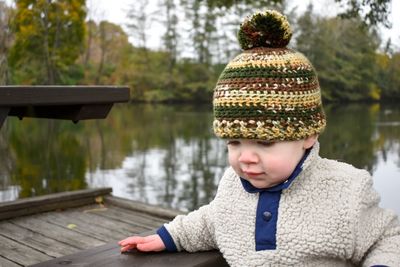 Close-up of boy sitting by lake against trees