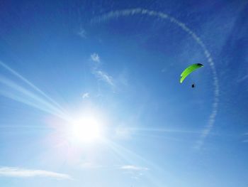 Low angle view of paragliding against blue sky