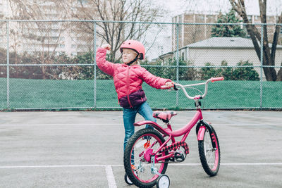 Girl standing with bicycle on walkway in city