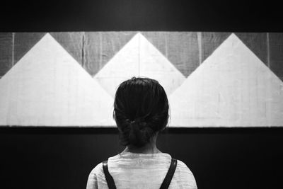 Rear view of girl standing by wall