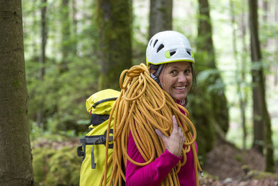 Portrait of smiling young man standing on tree trunk in forest