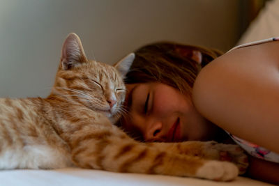 Girl lying with cat on bed at home