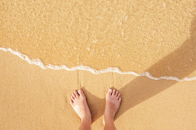 Low section of man standing at sandy beach