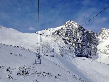 Overhead cable car on snowcapped mountains against sky