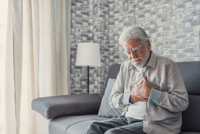 Portrait of young man sitting on sofa at home