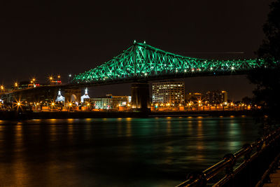 Illuminated bridge over river at night