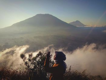 Young woman standing against mountain during sunrise