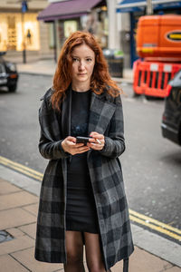 Young woman using mobile phone while standing on street
