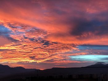 Scenic view of dramatic sky over silhouette landscape