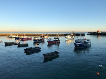 Boats moored in sea against clear sky