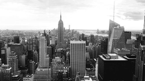 Empire state building in city against sky