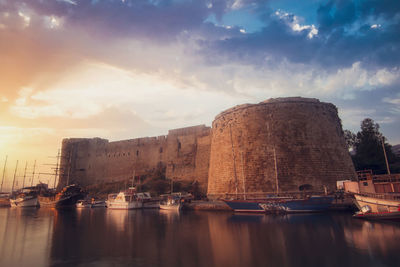 Boats moored at harbor against sky during sunset