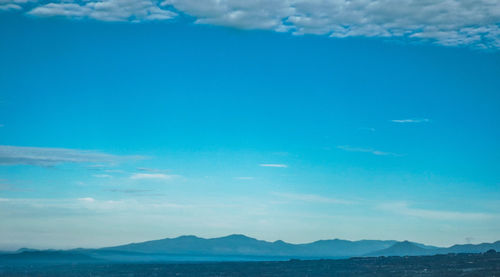 Scenic view of sea and mountains against blue sky