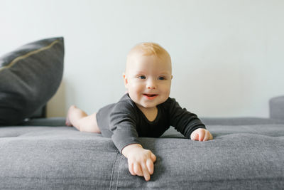 Portrait of cute boy sitting on sofa at home