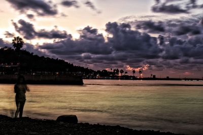 Silhouette man by sea against sky during sunset