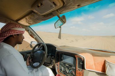 Man driving car on landscape against sky