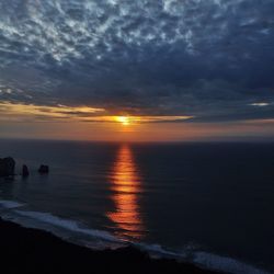 Scenic view of sea against cloudy sky at sunset