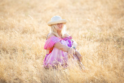 Woman with hat sitting on field in sunshine