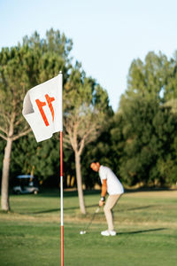 Attentive male athlete with putter and ball in golf field looking forward on summer day