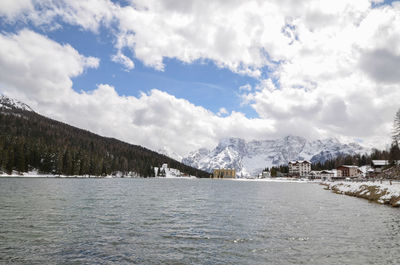 Scenic view of lake by snowcapped mountains against sky