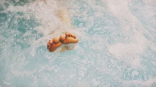 Low section of person swimming in pool