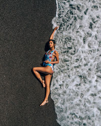 High angle view of young woman in swimwear lying at beach