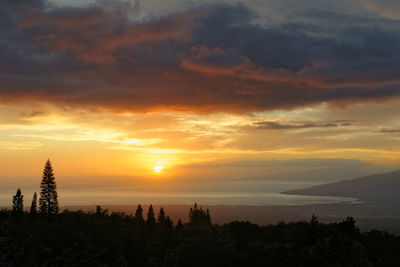 Colorful sunset in yellow and orange tones with dramatic dark clouds, hawaii, island of maui