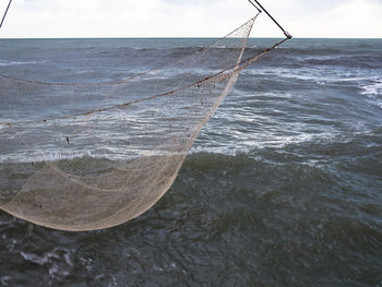 Close-up of fishing net at beach against sky