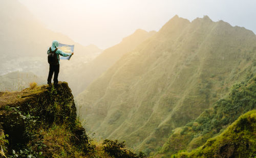 Rear view of man standing on mountain against sky