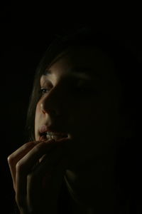 Close-up of young woman over black background