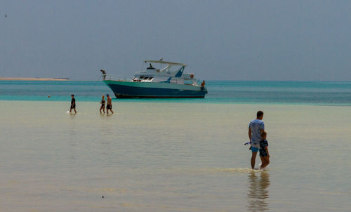 Rear view of people at beach against sky