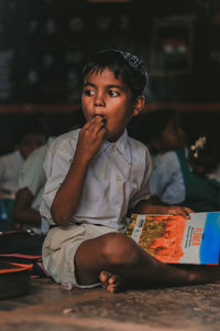 Boy looking away while sitting on table