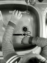 High angle view of young boy at kitchen sink