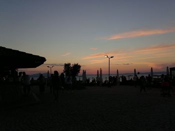 Silhouette people on beach against sky during sunset