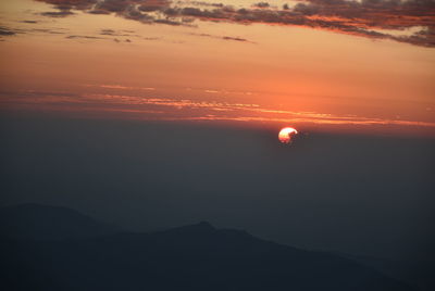 Scenic view of silhouette mountains against orange sky