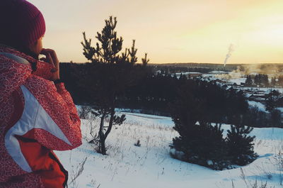 Woman standing on snow covered field against sky