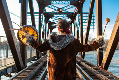 Rear view of man standing on railing