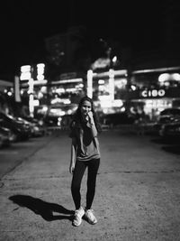 Full length of woman standing on street in city at night