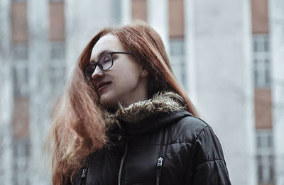 Happy young woman standing against building in city