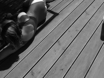 Rear view of mid adult woman in swimwear lying on hardwood floor during sunny day