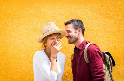 Young couple kissing against yellow wall