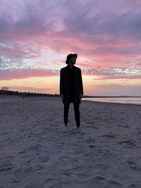 Man standing on beach against sky during sunset