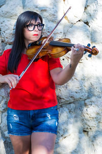 Woman playing violin against stone wall